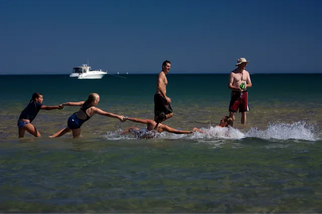 Four kids linked in a human chain playing in Lake Michigan surf
